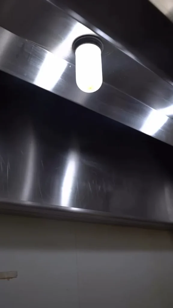 Clean stainless kitchen hood with the hood lights on after service