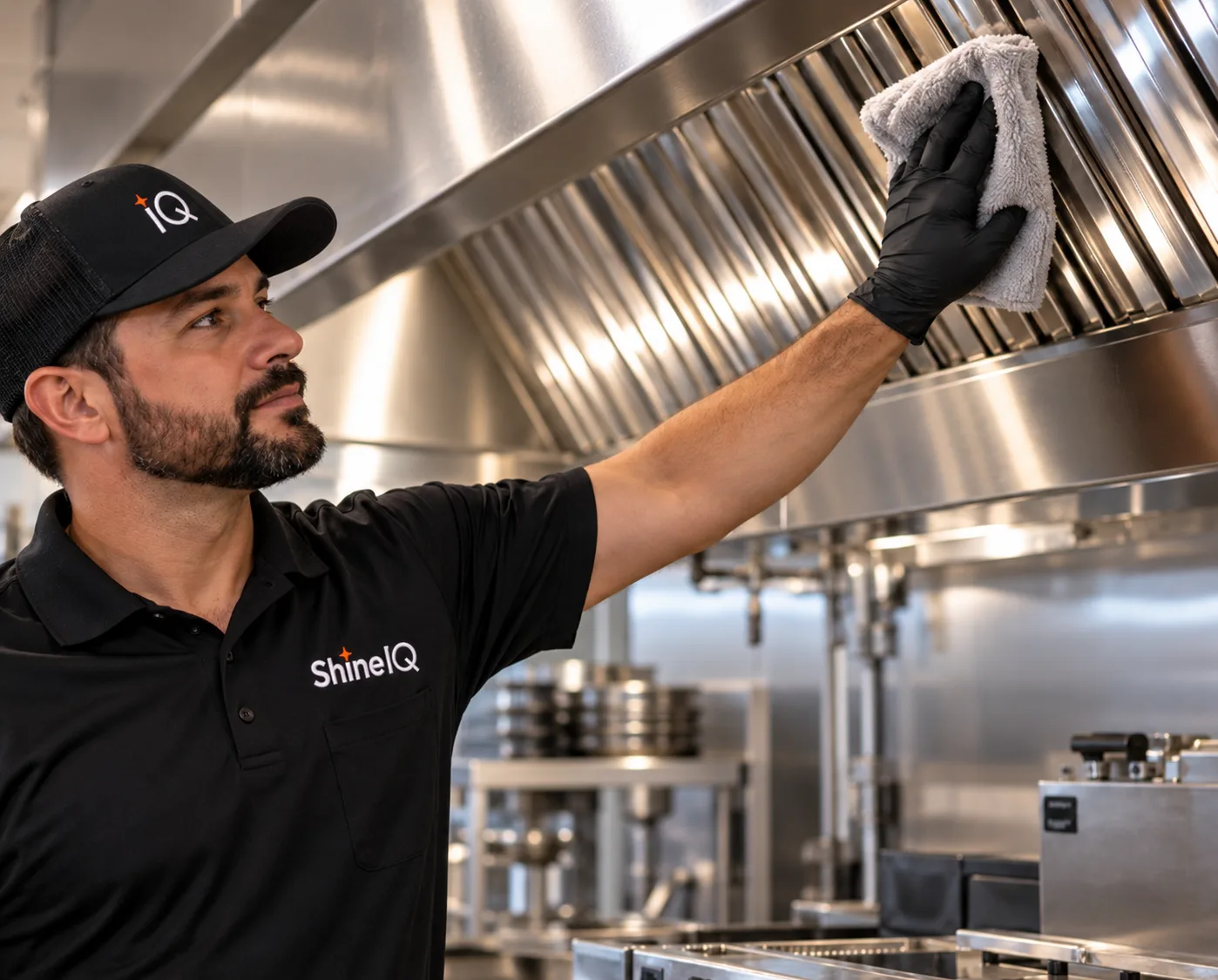 ShineIQ technician wiping down a stainless steel kitchen exhaust hood