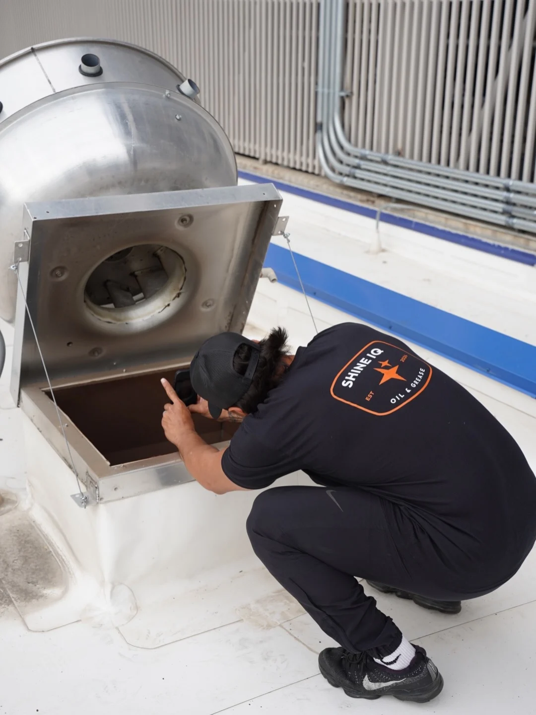 Technician inspecting an open rooftop exhaust fan access panel