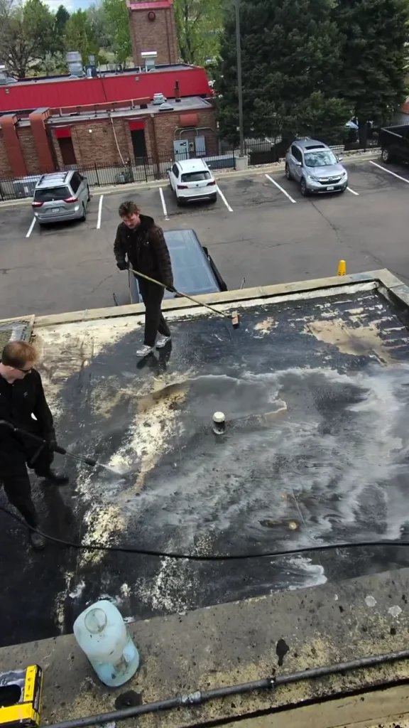 Technician cleaning grease off a restaurant roof near the exhaust fan