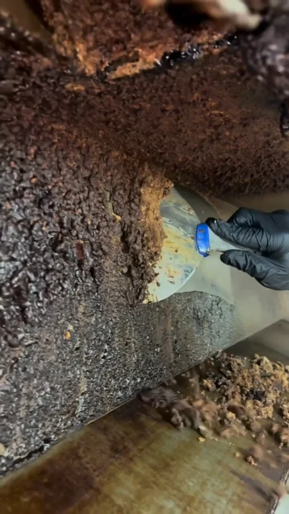Scraping grease buildup inside a kitchen hood
