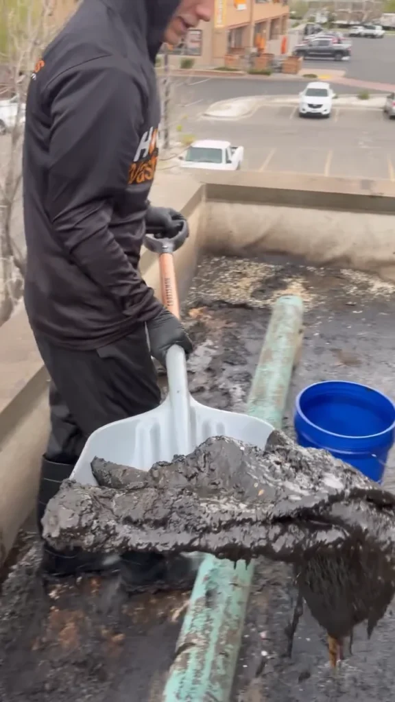 Technician shoveling grease off a restaurant rooftop