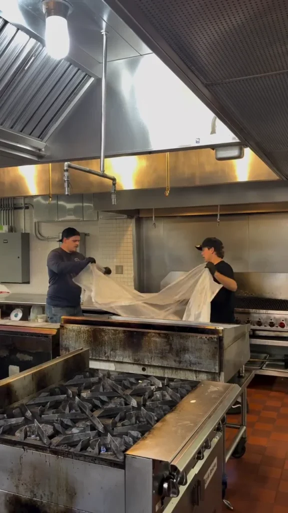 Technicians wrapping a cooking line in plastic before hood cleaning
